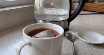 Tasse mit Teebeutel neben dem Wasserkocher