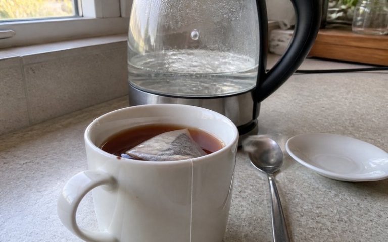 Tasse mit Teebeutel neben dem Wasserkocher